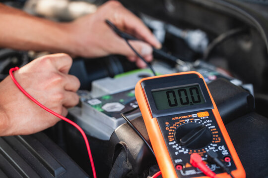 Car engine diagnostic testing with multimeter to assess electrical system at a garage