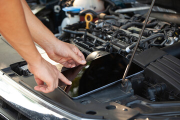 Mechanic uses tablet to diagnose car issues under the hood at a garage