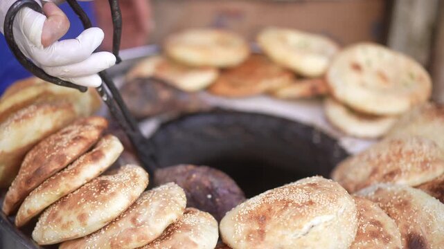 Freshly baked naan bread being removed from a traditional Uyghur tandoor oven in Xinjiang