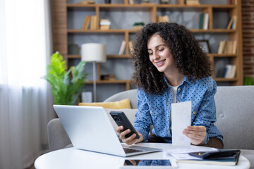 Smiling woman managing home finances using laptop and smartphone