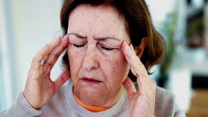 Mature woman enduring intense headache, eyes closed, hands on temples. Expression and facial lines convey severe pain, stress, burden of mental fatigue, physical or emotional strain-SD 480p