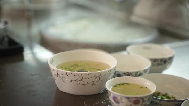 Celadon ceramic small bowls filled with green tea soup placed on a dining table
