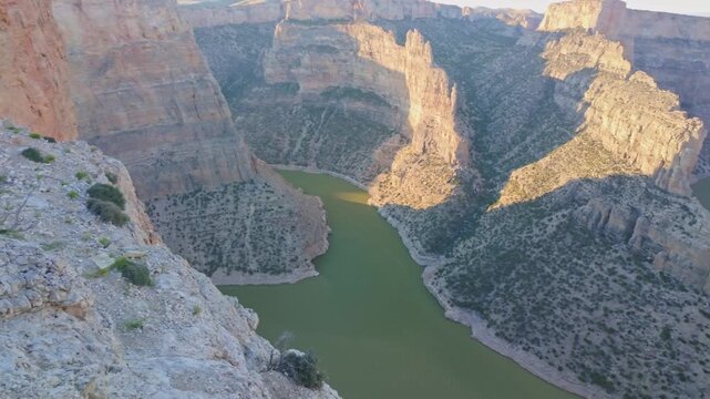 A breathtaking scenic view of a golden sunset from Devil's Canyon Overlook, casting a warm glow over the dramatic landscape of Bighorn Canyon