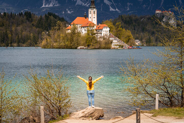 Mujer turista disfrutando del lago Bled, con los brazos abiertos en señal de alegría y plenitud © Javier