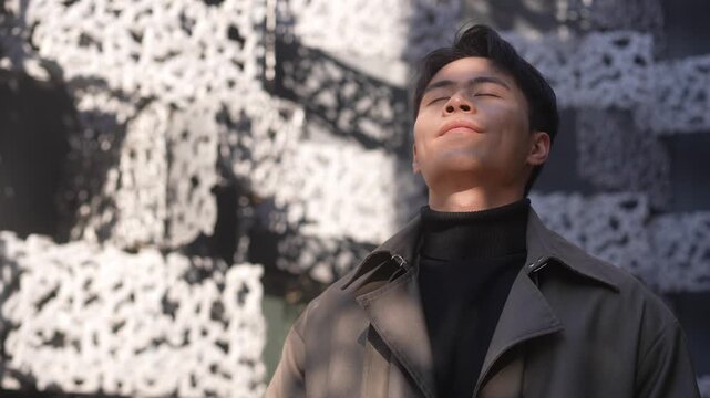 Young man looking upward toward the sky with a weathered textured wall in the background