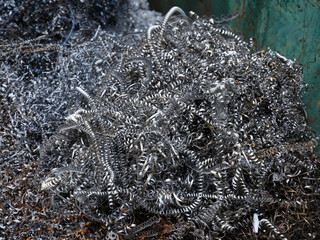 Close-up a metal shavings for further processing in large metal container for production waste.
