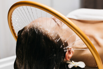 Woman receiving hydromassage therapy with gentle water jets, relaxing in a serene spa environment, showcasing the soothing benefits of aqua massage and Japanese head spa techniques