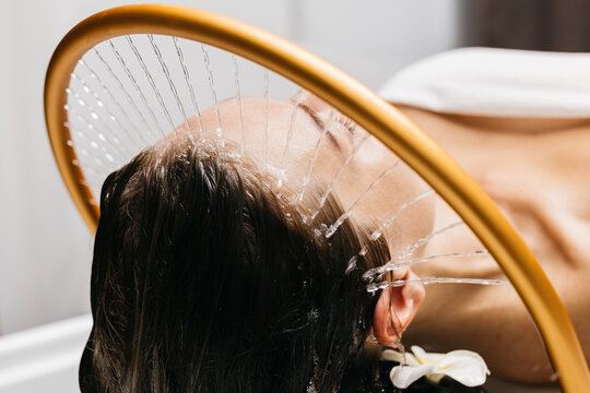 Woman receiving hydromassage therapy with gentle water jets, relaxing in a serene spa environment, showcasing the soothing benefits of aqua massage and Japanese head spa techniques