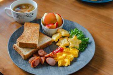 Breakfast plate with toast, scrambled eggs, sausage, fruit, and soup
