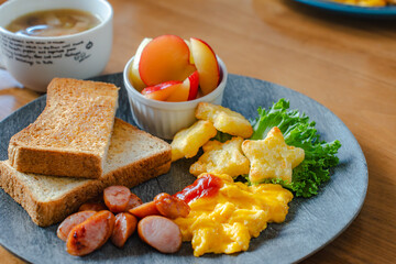 Breakfast plate with toast, scrambled eggs, sausage, fruit, and soup
