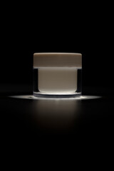 Elegant cosmetic jar with light reflection on black background