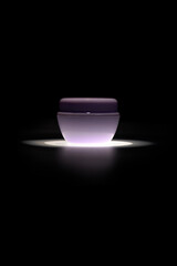 Elegant cosmetic jar with light reflection on black background