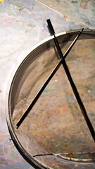 A curved, translucent enclosure, supported by two dark supports, sits amidst a surface speckled with paint.