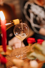 Close-up of white wine being poured into a glass at elegant candlelit dinner celebration