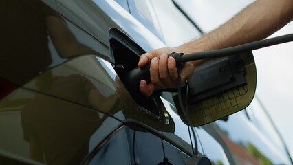 Close up of driver recharging EV vehicle battery powering sustainable electric motor, low angle...