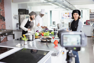 Diverse culinary team recording a cooking class lesson on camera, teaching food prep and plating techniques for an internet audience. Chefs hosting a video tutorial master course.