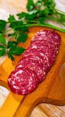 Sliced salami on a wooden board with parsley (1)