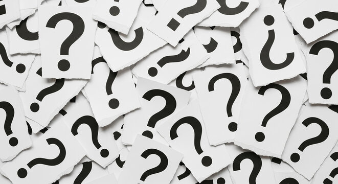 Pile of torn paper pieces with black question marks, symbolizing uncertainty, inquiry, or problem-solving