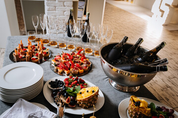 Luxury catering table with snacks, champagne bottles and glasses at elegant event