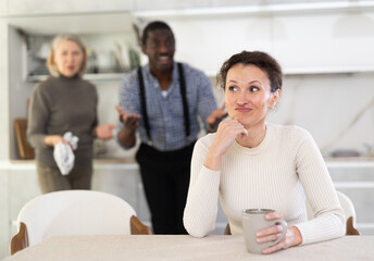 Upset woman not talking after disagreement with husband and mother standing behind