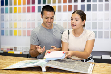Obraz premium Married couple together choose color of ceramic tiles from catalog in a hardware store