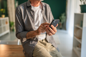 Senior man using smart phone at home: browsing internet and staying connected