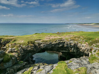 Fototapeta premium Fairy bridges in Bundoran, county Donegal, Ireland. Famous sea stacks and major original tourist attraction and view point. Blue ocean and cloudy sky in the background. Travel and tourism