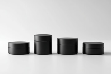 Four black cosmetic jars of varying sizes on a white background