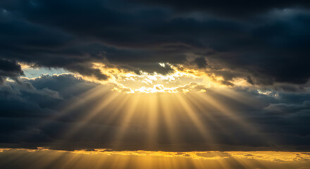 Dramatic sky displaying sun rays piercing through dark clouds creating a beautiful heavenly effect.