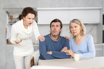 Wife quarrels with her husband in kitchen, and elderly mother calms son