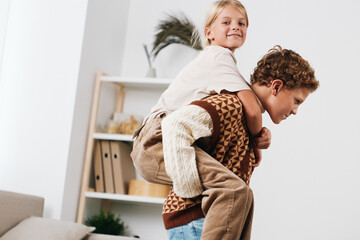 Authenticity shines in a cozy home scene as children play together, one on another's back, warm light and simple textures capturing a candid moment of everyday life.