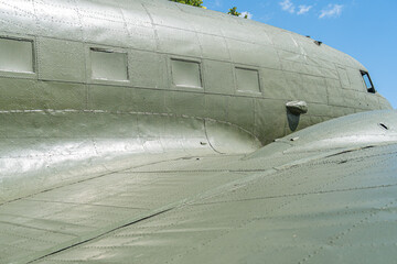 Large military cargo plane, olive green, parked on asphalt, clear sky with scattered clouds,...