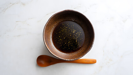 Fototapeta premium Soy sauce in a bowl with wooden spoon on marble table, top view isolated on white background