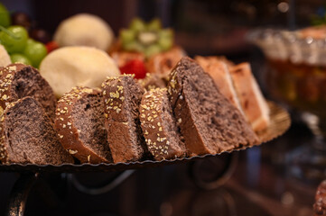 sliced dark grain bread with seeds for a party, fresh loaves of whole grain bread served on a plate, assorted artisanal breads and rolls for a buffet, healthy and rustic bread for a special breakfast
