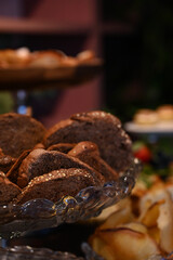sliced dark grain bread with seeds for a party, fresh loaves of whole grain bread served on a plate, assorted artisanal breads and rolls for a buffet, healthy and rustic bread for a special breakfast
