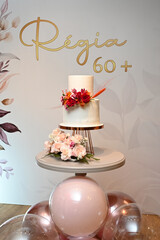 Elegant 60th birthday cake with pink flowers, white single-tier cake for milestone celebration, floral birthday cake with balloons, stylish cake display for 60+ birthday