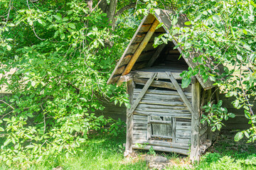 Ancient, rustic shed or outhouse in a Central European village amidst lush green trees Weathered...