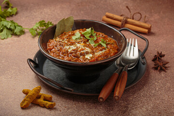 Dal makhani with cream and coriander leaves served in rustic bowl, accompanied by spices such as turmeric, cinnamon, and star anise, authentic Indian dish