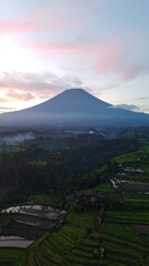 Majestic volcano rising above terraced rice paddies at sunrise