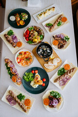 Assorted grilled meats and vegetables on plates, served with sauces and fresh herbs