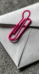Close-up of white envelope with pink paperclip