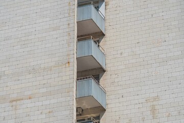 Metal staircase built into a light stone wall, enclosed by vertical metal bars Daytime setting with natural lighting from the left Architectural style, no human activity or contextual elements visi