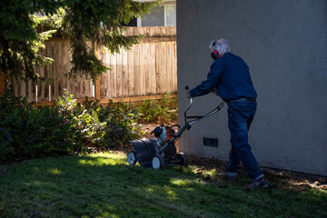 Lawn care and maintenance, senior man operating a gas powered dethatching machine on a grass lawn,...