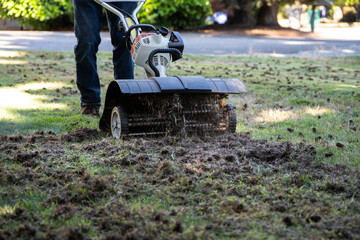 Closeup of dethatching machine tossing up pieces of dead lawn thatch and moss, grass lawn care and...