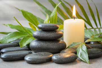 Obraz premium Spa Massage Stones with Candle and Green Leaves