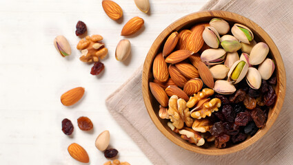 Overhead shot of a wooden bowl filled with mixed nuts and raisins on a white table