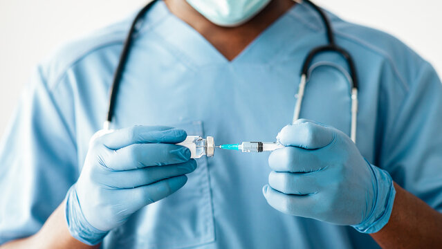 Covid-19 vaccine, antiviral injection, pharmaceutical and healthcare. Young african american doctor in protective mask, uniform and gloves dials vaccine in syringe, close up, copy space, cropped