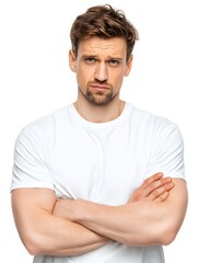 Obraz premium A young man with a skeptical expression crosses his arms while wea a white t-shirt on a white backdrop.