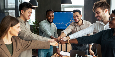 Success And Connection Concept. Smiling multiracial group of diverse business people making fist bump standing in circle. Happy colleagues pumping hands together as symbol of unity and achievement