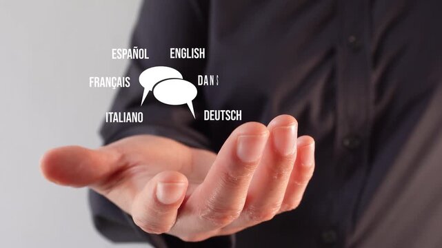 Translating conversations. A person's hand holding an animation of speech bubbles with different languages ​​around them.